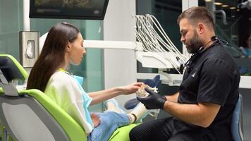 Dentist and patient choosing treatment in a consultation with medical equipment in the background video