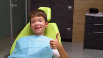 portrait de une content peu garçon à la recherche à caméra souriant tandis que séance dans une dentisterie après les dents examen video
