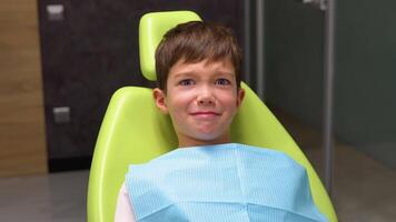 Frightened little boy sitting in dentist's chair and looking at camera video