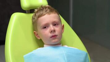 Sad little boy crying at reception at dentist in dental chair. Child is afraid to treat teeth video
