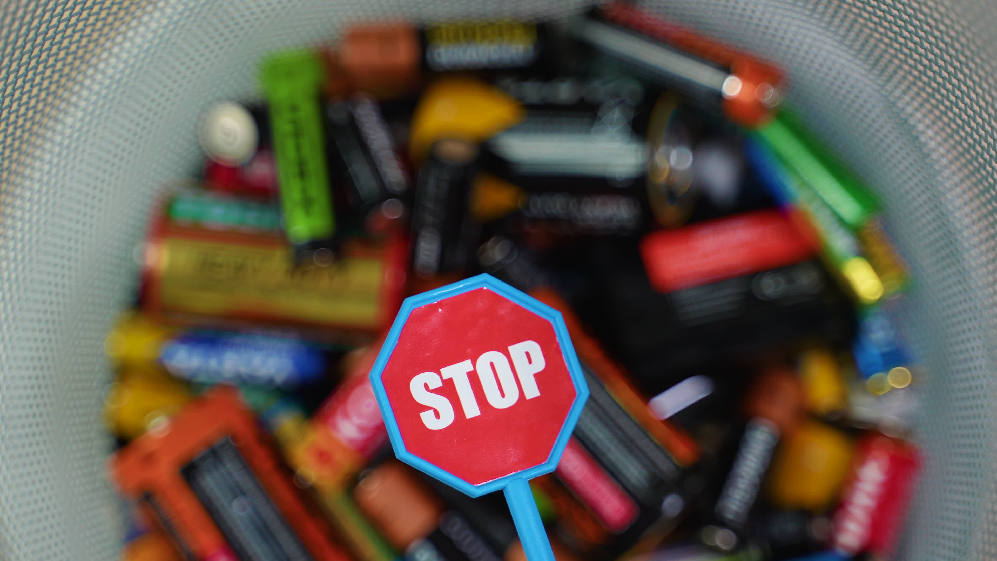 A person throws batteries into a bin. Stop pollution by batteries