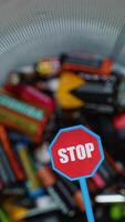 Stop pollution by batteries. Different battery and stop sign rotate in a bin. Old used batteries. Vertical video