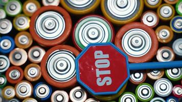 Stop pollution by batteries. Old used batteries type AA, AAA, D and stop sign rotate in a circle video