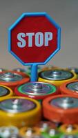 Old used batteries type AA, AAA, D and stop sign rotate in a circle. Vertical video