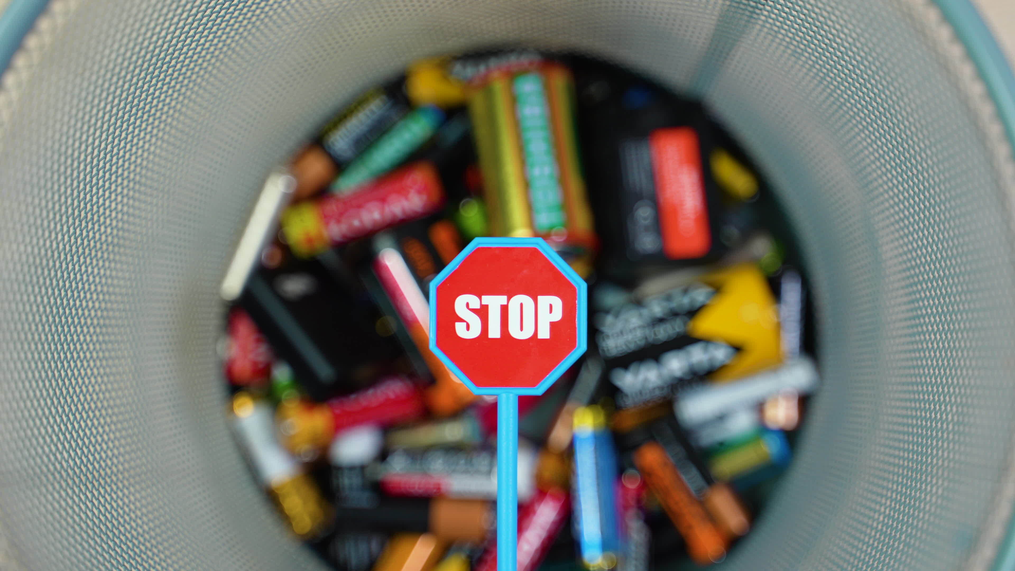 A person throws used batteries into office garbage bin. Stop pollution