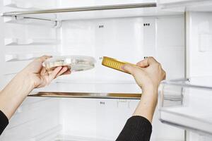 a person is holding a toothbrush in an open refrigerator photo