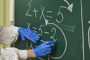 a person wearing blue gloves writing on a blackboard photo