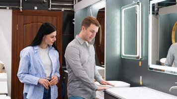 Young couple choosing new bathroom furniture at the plumbing shop with lots of sanitary goods video