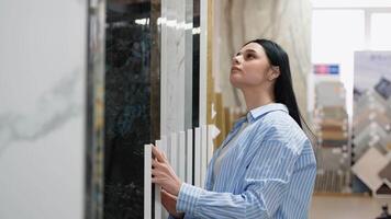 uma mulher escolhe cerâmico azulejos dentro uma hardware loja video