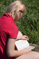 Young woman reads book outdoors in nature photo