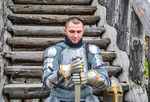 Knight in the armor on the wooden steps. Knightly armor and weapon photo