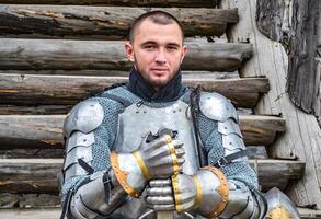 Knight in the armor on the wooden steps. Knightly armor and weapon photo