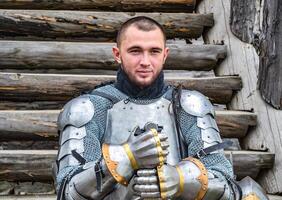 Knight in the armor on the wooden steps. Knightly armor and weapon photo