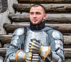 Knight in the armor on the wooden steps. Knightly armor and weapon photo