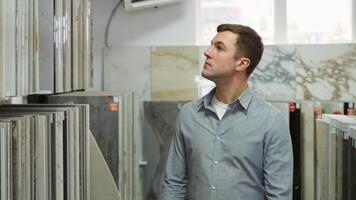 A man choosing ceramic tiles for his home bathroom while walking in hardware shop video