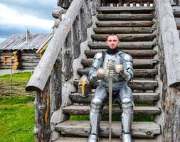 Knight in the armor on the wooden steps. Knightly armor and weapon photo