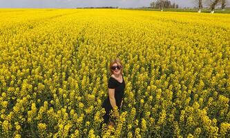 A girl in a black dress among the colors of rape in the field. W photo