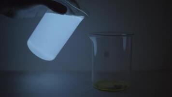 Glowing fluorescent substance mixed with clear water in chemistry bottle at lab video