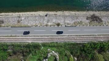 Car going on a road near the river, aerial view. Footage. Aerial view at small forest lake and line of highway passing near. Car going on a road near the river, aerial view. Footage. Aerial view video