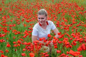girl sat in the middle of a poppy field. photo