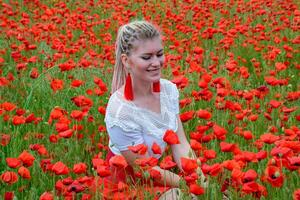 girl sat in the middle of a poppy field. photo