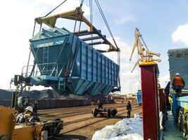 Rusia, novorossiysk 2021. levantamiento el tolva coche para descarga en un carga barco. levantamiento operaciones en el puerto. foto