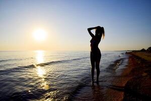 Silhouette of a girl against the sunset by the sea photo