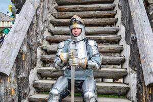 Knight in the armor on the wooden steps. Knightly armor and weapon photo
