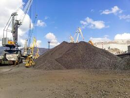 Heap of coal anthracite in the port. Port cranes for coal loading photo