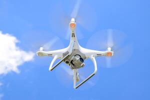 Drone DJI Phantom 4 in flight. Quadrocopter against the blue sky with white clouds. The flight of the copter in the sky. photo