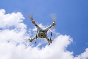 Drone DJI Phantom 4 in flight. Quadrocopter against the blue sky with white clouds. The flight of the copter in the sky. photo