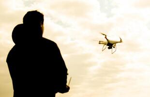 A man with a remote control in his hands. Controlling the flight of the drone against the sky. Phantom. photo