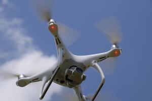 Drone DJI Phantom 4 in flight. Quadrocopter against the blue sky with white clouds. The flight of the copter in the sky. photo