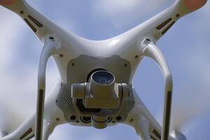 Drone DJI Phantom 4 in flight. Quadrocopter against the blue sky with white clouds. The flight of the copter in the sky. photo