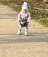 The child is playing with the ball. A little four-year-old girl plays with a football. photo