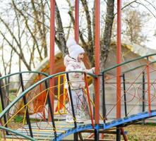 Little girl is playing on the playground in the park. The child goes on the steps of the playground. photo