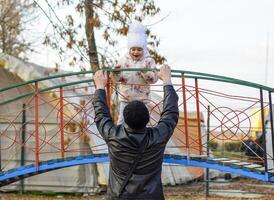 Dad plays with his daughter on the playground in the park. Autumn walk of the family. photo