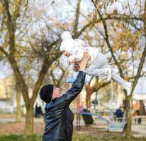 joyful father tosses his daughter up. Walk the family in the park in the fall. photo