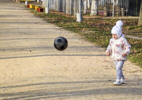 el niño es jugando con el pelota. un pequeño niño de cuatro años niña obras de teatro con un fútbol. foto