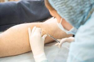 Dermatologist surgeon gives pain relief with an injection instead of surgery, close up view of operation process. High quality photo