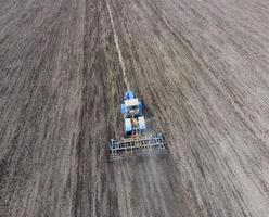 The tractor plows the field. Under sowing, the soil is loosened on the field. photo