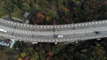 Top view on overpass with driving cars, sea and beautiful landscape background. Aerial view of highway and overpass in city. Road junctions video