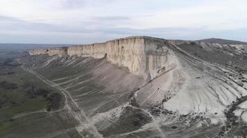 aérien pour magnifique paysage de blanc Roche avec raide pente et une vallée avec vert herbe. tir. blanc calcaire avec une verticale falaise sur bleu, nuageux ciel Contexte. video