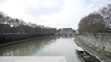 hermosa ver de un río con lento fluir y antiguo puente con muchos arboles creciente a lo largo el río. existencias. otoño paisaje de un río, puente y un tráfico mermelada a lo largo el acera. video