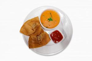 sopa y 2 piezas profundo frito wontons con inmersión salsa en un blanco plato en un blanco antecedentes. frito wontons albóndigas, en tailandia, Wonton es llamado kiao. foto