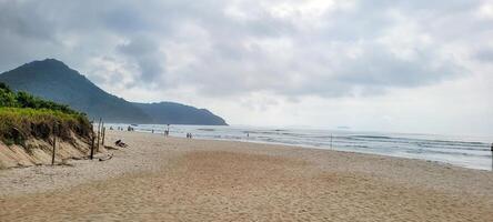 image of beach with white sand and calm sea on sunny day with bathers and surfers on the beach photo