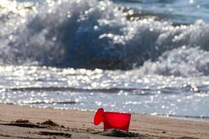 Plastic can scoops up pink sand at Pattaya beach. photo