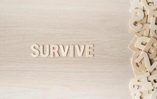 The word SURVIVE, Wooden letters on a wooden table. photo
