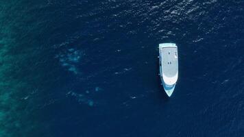 Motor boat and divers underwater in blue tropical sea near reef wall on Maldives. Aerial view video