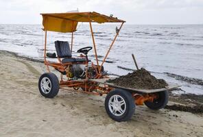 The car for garbage collection from the beach. Cleaning on the beach, clean beach from mud and waste photo